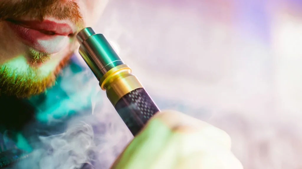 Close-up of a person using a vaporizer pen surrounded by vapor, illustrating modern cannabis vaporization techniques for cleaner inhalation.