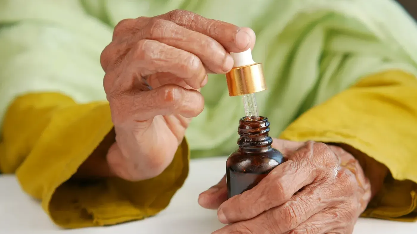 Senior using CBD oil dropper bottle