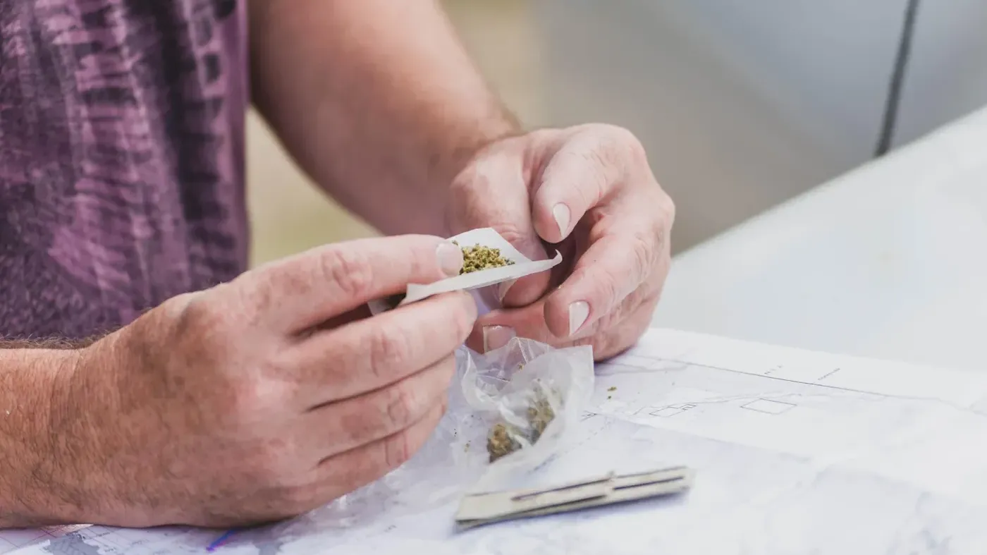 Rolling paper with cannabis, bag on table