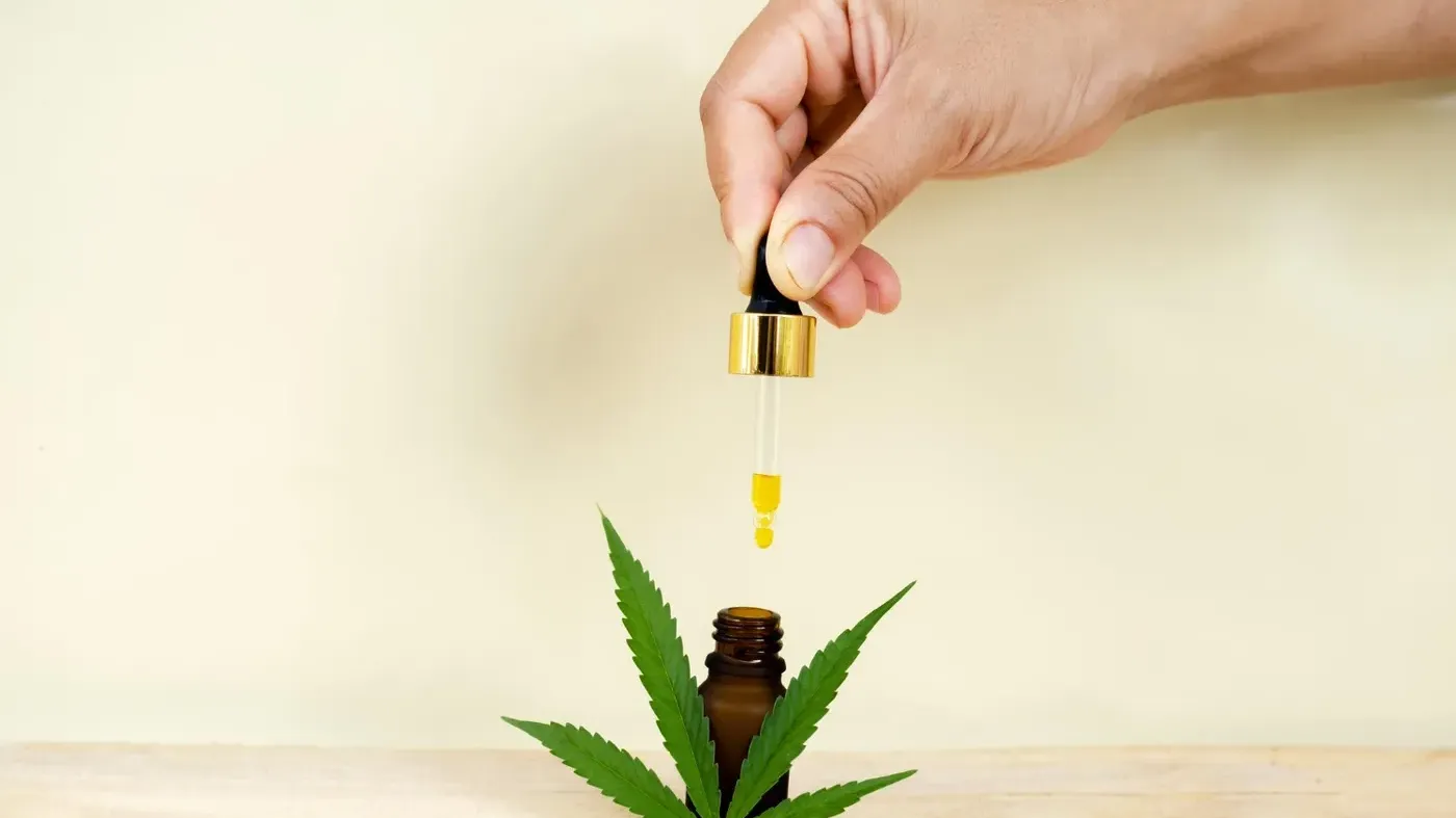 person dropping cannabis oil in jar