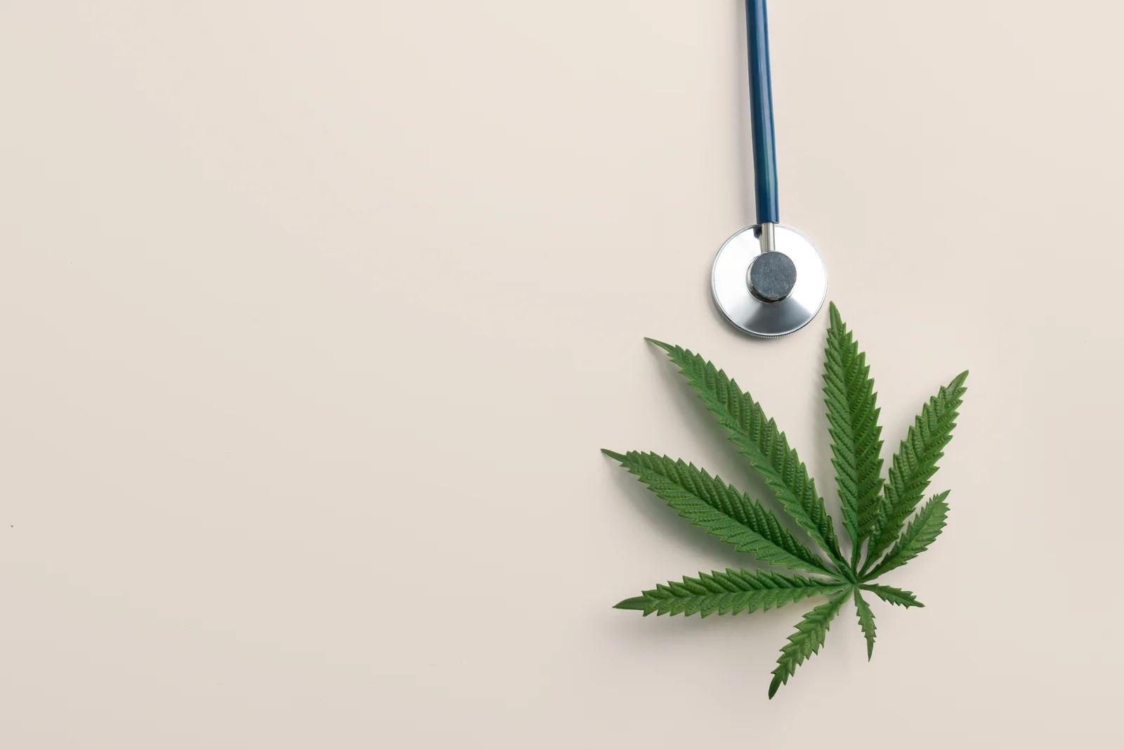 Stethoscope beside a cannabis leaf on a neutral background, symbolizing the connection between ADHD and Medical Cannabis in modern healthcare.