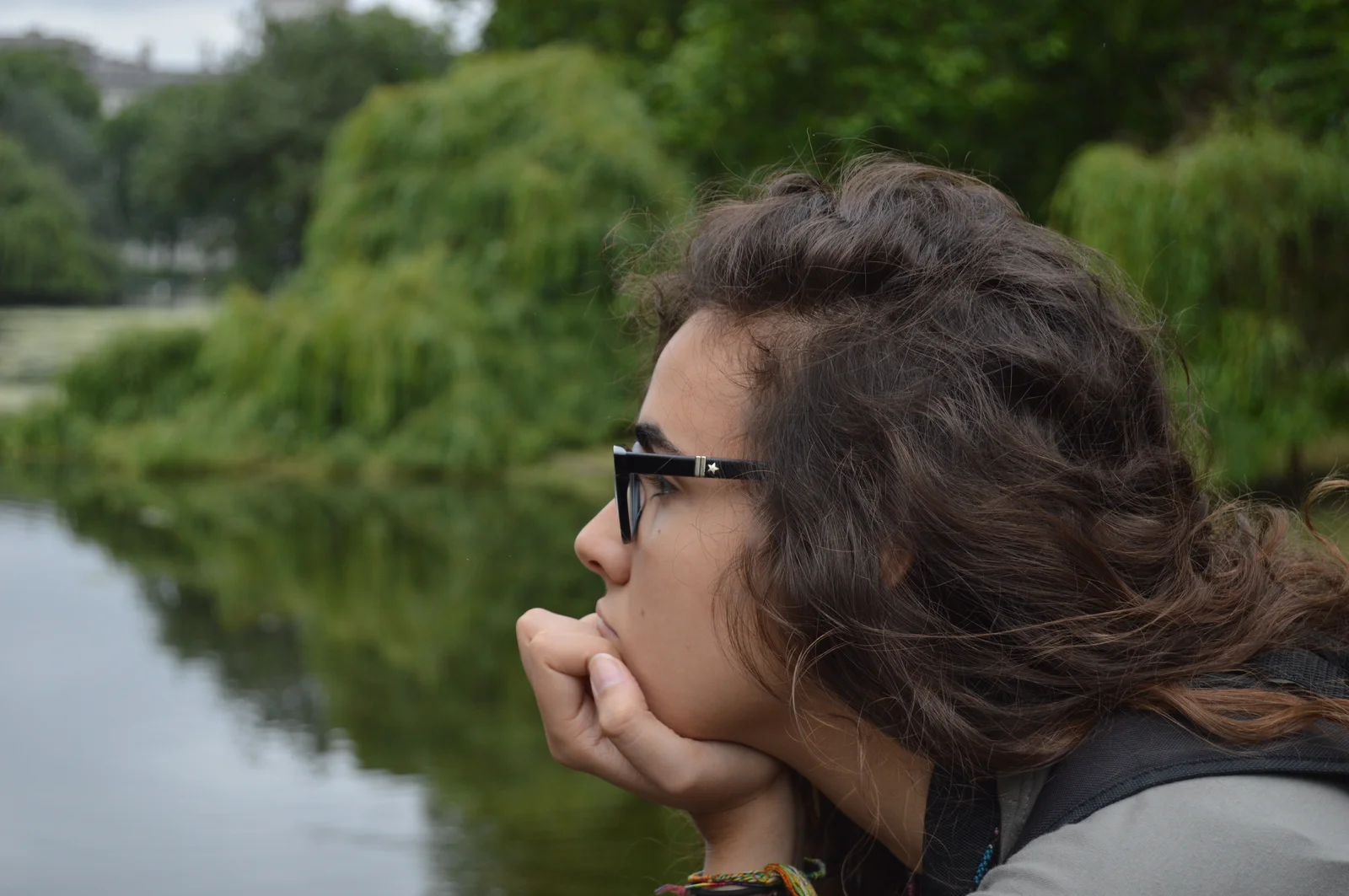 A thoughtful woman staring out over a calm lake, illustrating the reflective mindset and enhanced concentration associated with cannabis for focus.