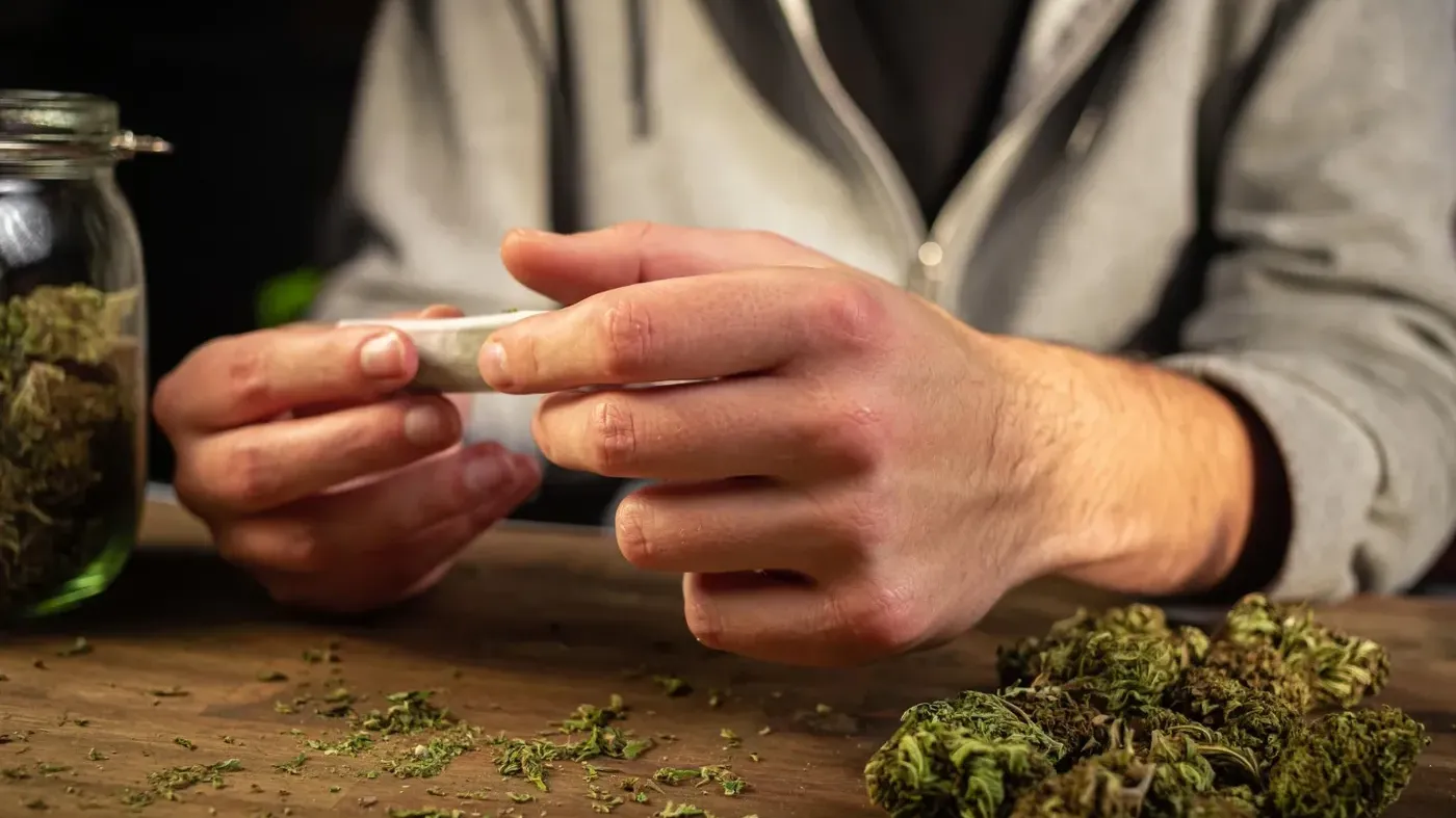 person rolling a joint on table showcasing best cannabis strains for adhd